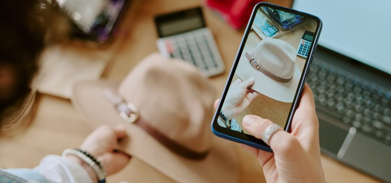 woman taking picture of a hat with mobile phone